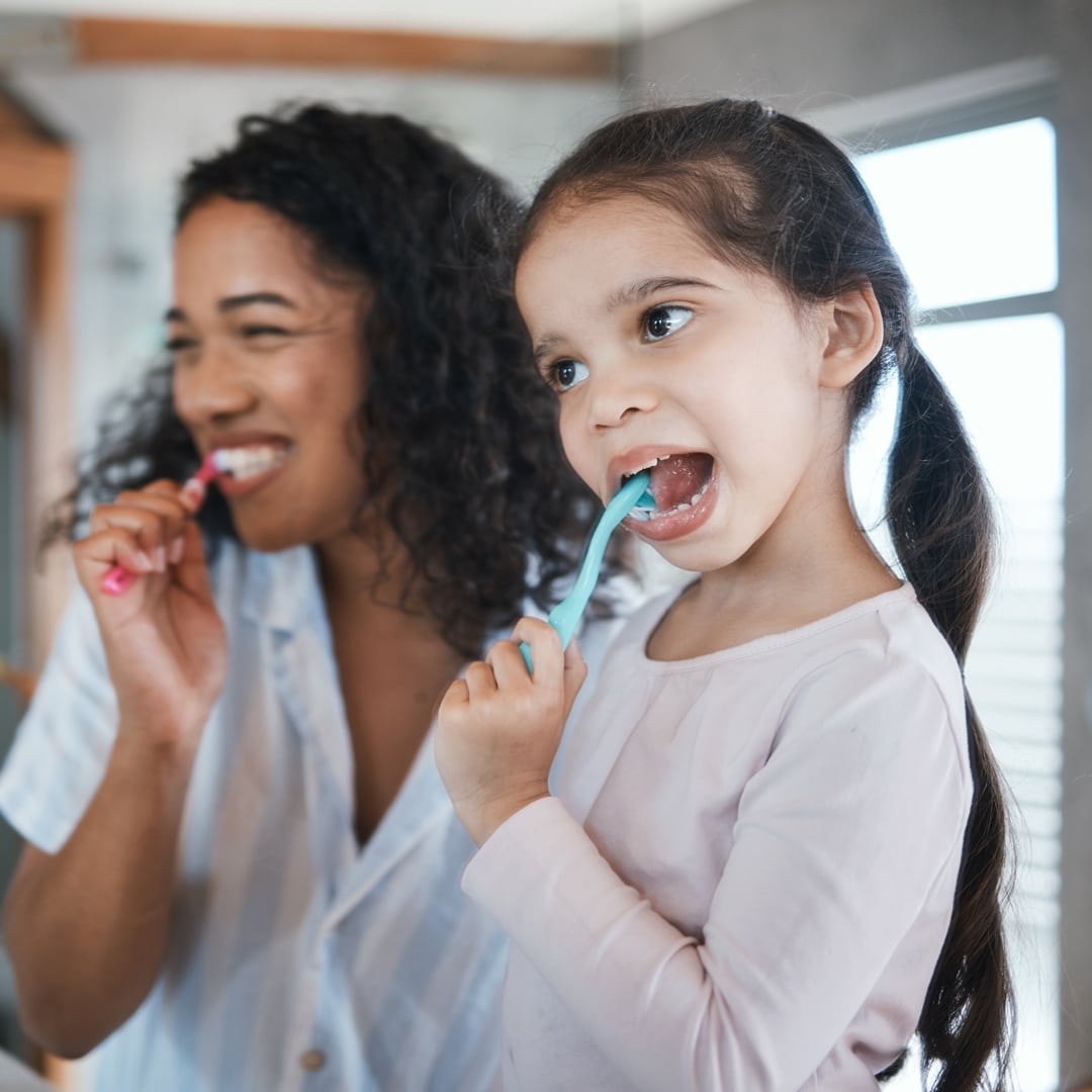 mother and daughter brushing their teeth in the bathroom