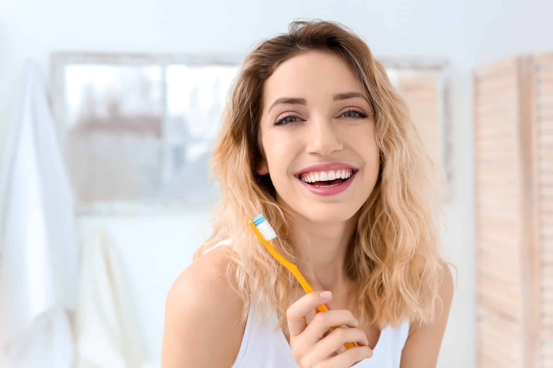 patient brushing her teeth after a dental whitening service at oxford dental in mount pleasant wi